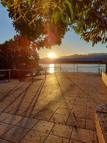 a sunset over the water with a pier in the background at Pousada Ninhal das Garças in Ilha Comprida