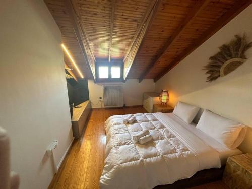 um quarto com uma grande cama branca e um tecto de madeira em Caja De Anthea em Artemida