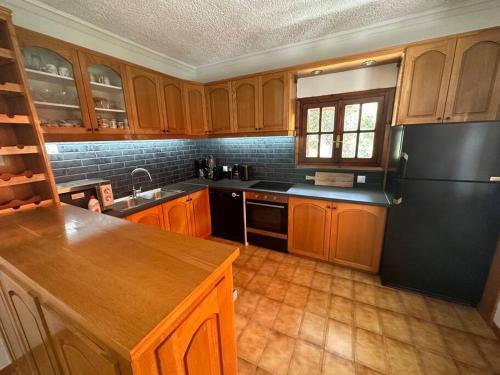 a kitchen with wooden cabinets and a black refrigerator at Caja De Anthea in Artemida