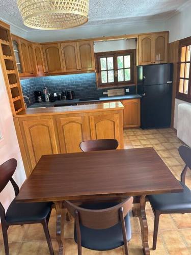 a kitchen with a wooden table with chairs and a refrigerator at Caja De Anthea in Artemida