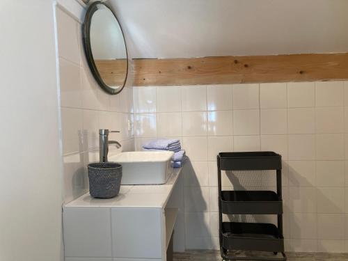 Baño blanco con lavabo y espejo en Gîte de 12 personnes au cœur d'un domaine viticole en Gruissan