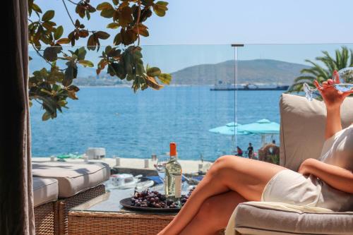 Una donna seduta su una sedia vicino all'acqua di Porto Eda Hotel a Sarandë