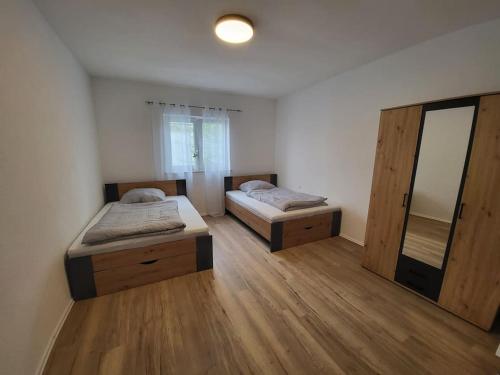 Duas camas num quarto com pisos em madeira em Wohnung in Crailsheim/Satteldorf 