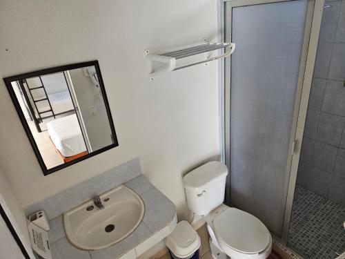 a bathroom with a toilet and a sink and a mirror at El Padrino in Akumal