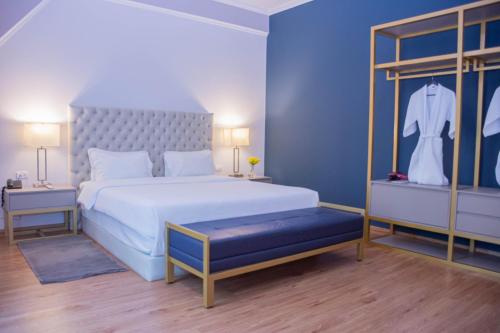 a bedroom with a white bed with a blue wall at Bisinii Boutique Hotel in Ciudad del Este