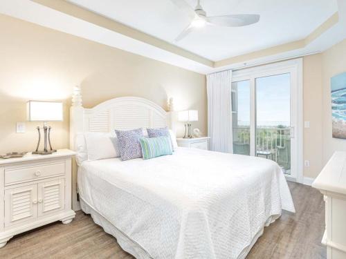 een witte slaapkamer met een wit bed en een raam bij Beach House 413 in Tybee Island