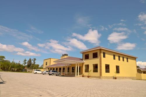 ein gelbes Gebäude mit Autos auf einem Parkplatz in der Unterkunft Rossina Living in Naivasha