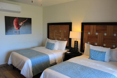 a hotel room with two beds and a bird on the wall at Sawari Hotel in San Carlos