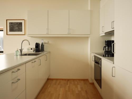 eine Küche mit weißen Schränken und einem Waschbecken in der Unterkunft Stunning 1-Bedroom Apt with Breathtaking Scenery in Tórshavn