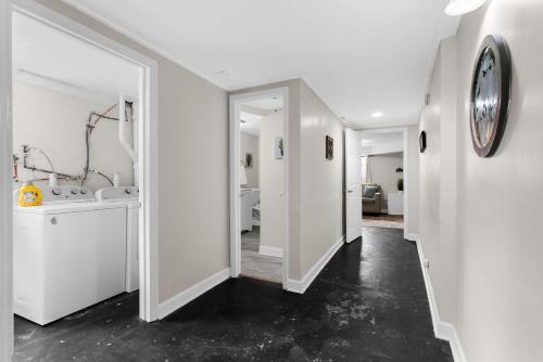 a hallway with white walls and a clock on a wall at 10 Mins to Downtown Modern in Magic City- Unit B in Birmingham