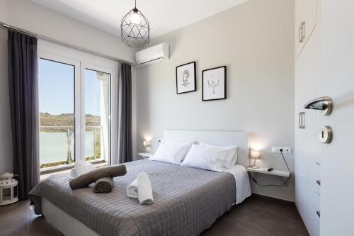 a bedroom with a bed and a large window at Nereides - Skinaria Beach Apartment in Damnoni