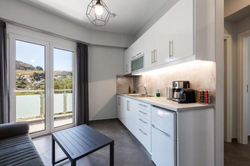 a kitchen with white cabinets and a large window at Nereides - Skinaria Beach Apartment in Damnoni