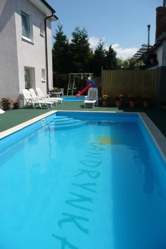 a blue swimming pool with two chairs and a playground at Pensjonat Landrynka in Darłówko