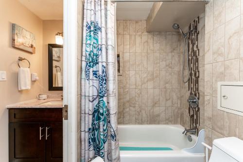 a bathroom with a tub and a shower curtain at The Location! Aloha Soul Beachfront in Laie