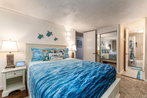 a bedroom with a blue bed and a bathroom at The Location! Aloha Soul Beachfront in Laie