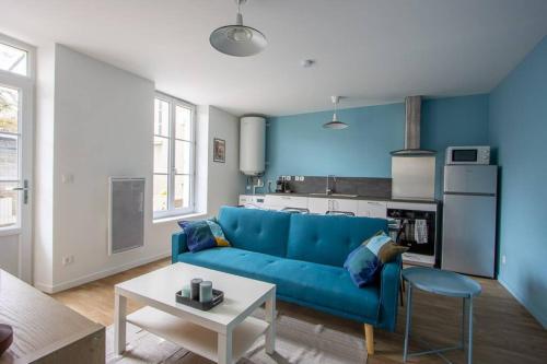 ein Wohnzimmer mit einem blauen Sofa und einem Tisch in der Unterkunft Appartement avec terrasse et parking, à Meaux in Meaux