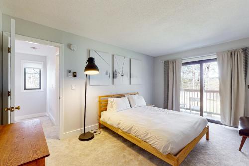 een slaapkamer met een bed, een tafel en een lamp bij Windsor Village 3E in Quechee