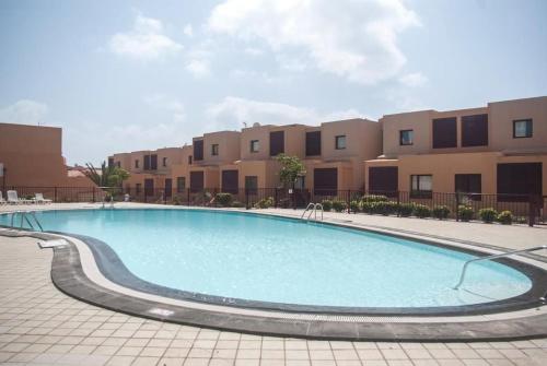 a large swimming pool in front of a building at Piscina & Wifi. SUNNY apartement, swimming pool. in Caleta De Fuste