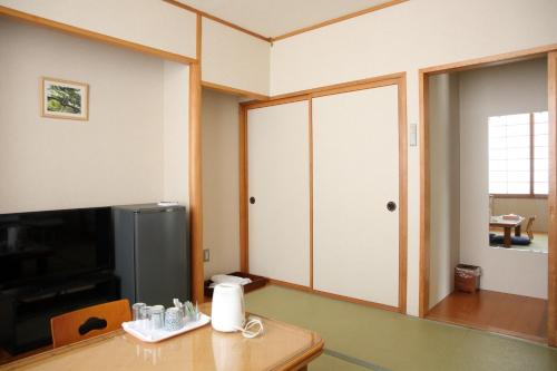 a room with a table and a tv and a door at Pinneshiri onsen Hotel Bogakuso - Vacation STAY 31516v in Pinneshiri
