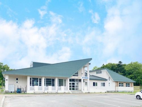 biały budynek z zielonym dachem i parkingiem w obiekcie Pinneshiri onsen Hotel Bogakuso - Vacation STAY 31617v w mieście Pinneshiri