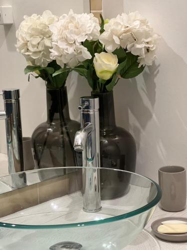 une table en verre avec deux vases aux fleurs blanches dans l'établissement Joli studio avec parking privé, à Moulins
