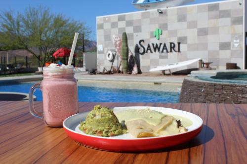 a plate of food and a drink on a table next to a pool at Sawari Hotel in San Carlos