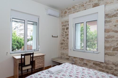 a bedroom with a bed and a desk and two windows at casa zervos - Abode of Light in Loutraki