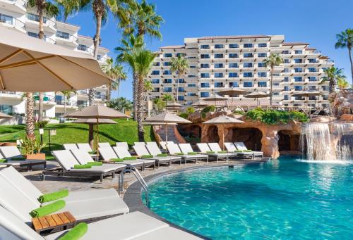 a swimming pool with chairs and a hotel in the background at Villa del Palmar Beach Resort & Spa in Cabo San Lucas