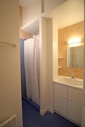 La salle de bains est pourvue d'un rideau de douche blanc et d'un lavabo. dans l'établissement Gîte La Chassagne - Gîte n°11, à Videix