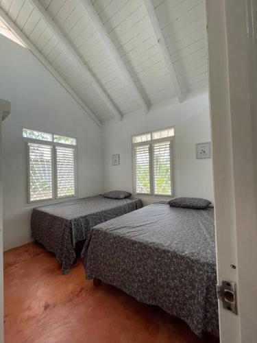 two beds in a room with two windows at Casa yaan in Las Galeras