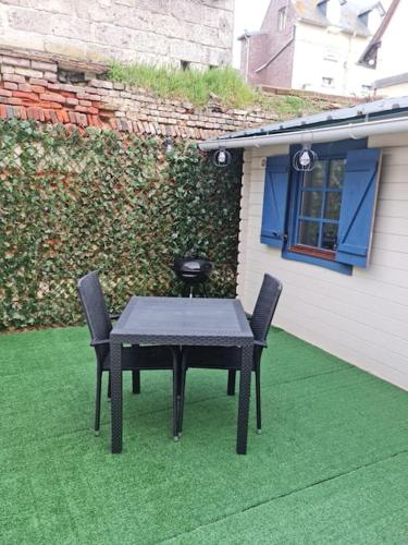 une table et deux chaises assises sur une pelouse dans l'établissement Chalet 25 m de la mer, à Ault