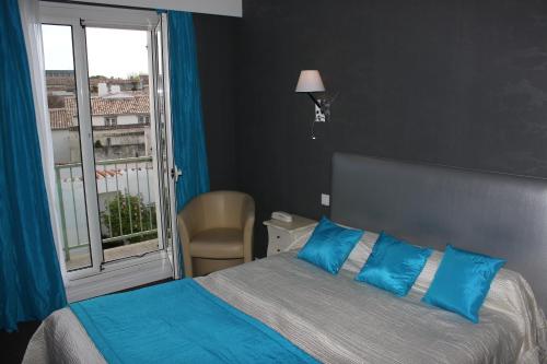 a bedroom with a bed with blue pillows and a window at Les Colonnes in Saint-Martin-de-Ré