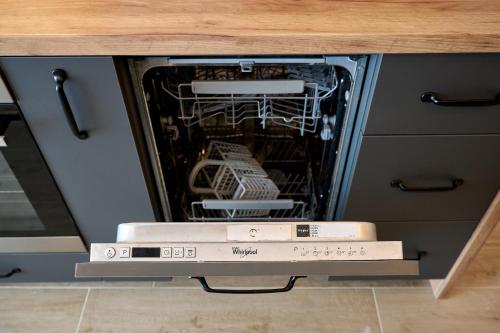 an open dishwasher with some dishes inside of it at La Mer by Infinity Resort & SPA in Mamaia Nord