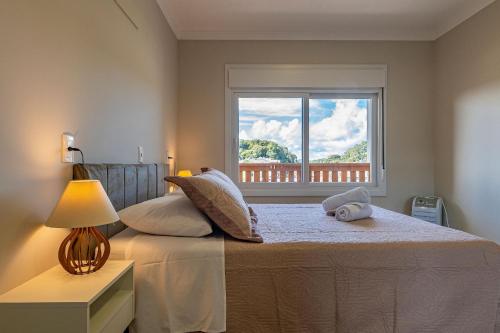 ein Schlafzimmer mit einem großen Bett mit Fenster in der Unterkunft Excelente ap em Canela - @stayhousetemporada in Canela