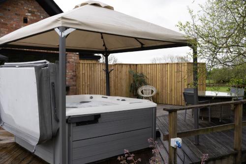 a hot tub with an umbrella on a deck at Luxury Retreat -Perfect To Explore The North Coast in Macosquin