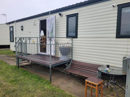 a mobile home with a bench and a table at Discover comfort home from home 8-birth Caravan in Skegness
