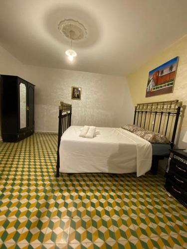 um quarto com uma cama e um piso amarelo e verde em Dar el oued em Tânger