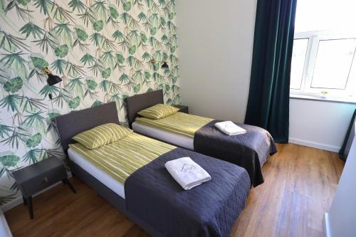 a room with two beds and a wall with leaves at Apartamenty GREY&WHITE in Ciechocinek