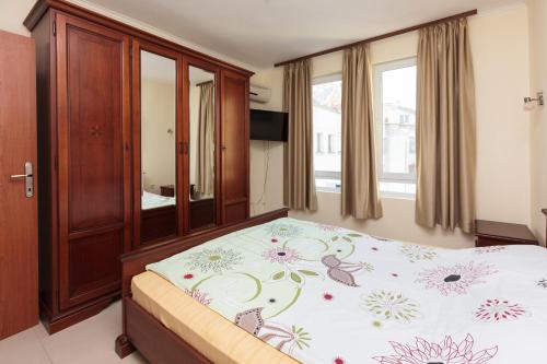 a bedroom with a bed with a floral bedspread at Apartment Patriarh Evtimiy in Burgas