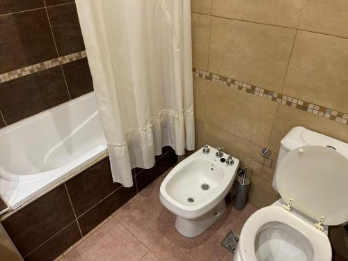 ein Badezimmer mit einem WC, einer Badewanne und einem Waschbecken in der Unterkunft Tu casa en parque in Necochea