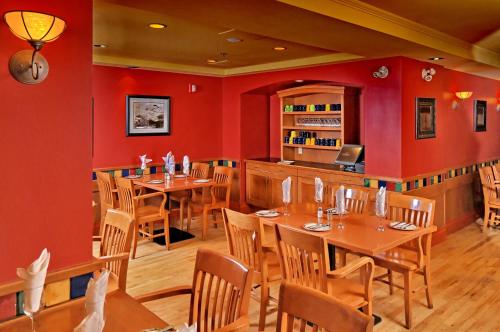 a restaurant with red walls and wooden tables and chairs at Banff Ptarmigan Inn in Banff