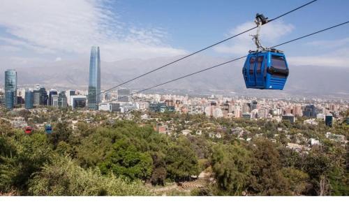 a blue cable car flying over a city at Comodo departamento metro Matta Santiago Centro in Santiago