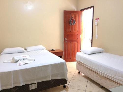 a bedroom with two beds and a door with a window at Hana Praia Hotel in Camocim