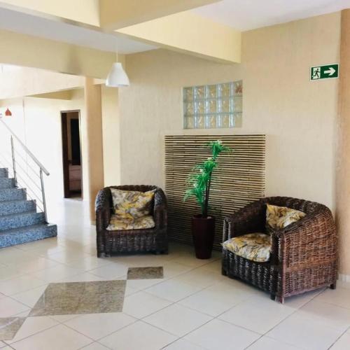 two wicker chairs and a plant in a living room at Hana Praia Hotel in Camocim