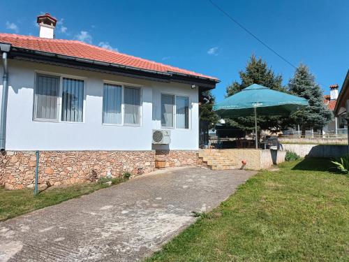 ein weißes Haus mit einem blauen Regenschirm im Hof in der Unterkunft Вила Текето in Obrochishte