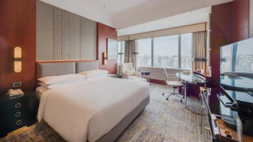 a bedroom with a large white bed and a desk and a desk at Shanghai Marriott Marquis City Centre in Shanghai