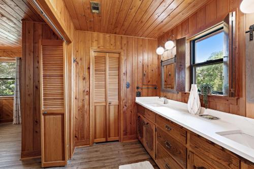 baño con paredes de madera, lavabo y ventana en Wolf Bay House, en Elberta