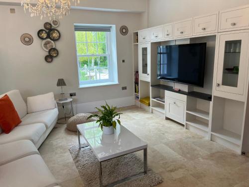 a living room with a white couch and a tv at Stunning and luxurious Manor House holiday home in Broadmayne