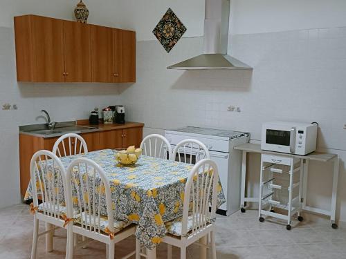 una cucina con tavolo, sedie e forno a microonde di CASA VACANZE ALBA a Pozzallo