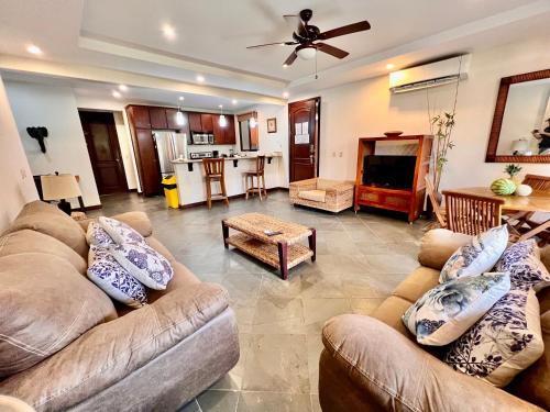 a living room with two couches and a kitchen at Monte Carlo Luxury Condominiums in Jacó